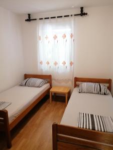two beds in a room with a window with flowers at Apartments Villa Venera in Ražanac