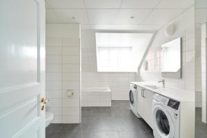 a white bathroom with a washing machine and a sink at Beautiful 3 Bedroom Flat Near Shopping & Metro in Copenhagen