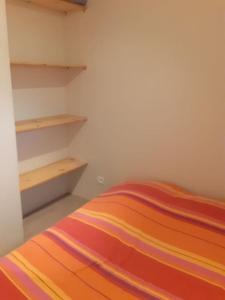 a bedroom with a bed with a colorful striped blanket at La cabane au fond du jardin in Montrodat