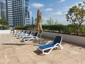 a row of chaise lounge chairs and an umbrella at White Sage - Gorgeous Apartment in JLT Near the Metro Station in Dubai