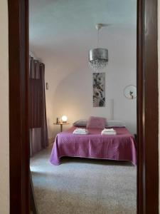 - une chambre avec un lit et une couverture violette dans l'établissement Da Julia, à Oristano