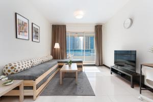 a living room with a couch and a television at White Sage - Gorgeous Apartment in JLT Near the Metro Station in Dubai