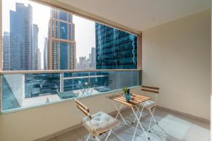 a balcony with a table and chairs and a large window at White Sage - Gorgeous Apartment in JLT Near the Metro Station in Dubai