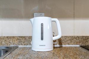 a white electric kettle sitting on a kitchen counter at White Sage - Gorgeous Apartment in JLT Near the Metro Station in Dubai