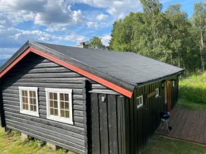 a small black shed with a red roof at Ljoshaugen Camping in Dombås