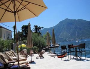 a group of chairs and tables with umbrellas and the water at Vila Nikčević Apartments in Kotor