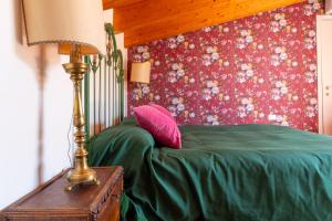 a bedroom with a bed with a green comforter and a lamp at La Chiesuola in Viterbo