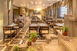 a restaurant with tables and chairs and plants at Hotel Kohinoor Continental,Airport in Mumbai