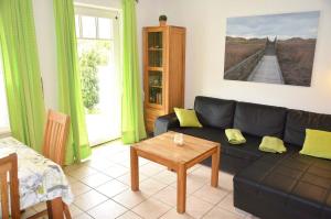 a living room with a black couch and a table at Zum Leuchtturm 10 Ferienwohnung Nr 05 in Westereck