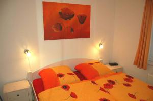 WestereckにあるZum Leuchtturm 10 Ferienwohnung Nr 05のベッドルーム1室(オレンジのシーツと花を使用したベッド2台付) +6枚の写真