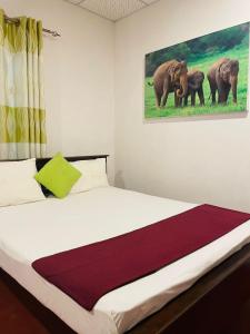 a bedroom with a bed with a picture of three elephants at Lake Island Home Stay in Dambulla
