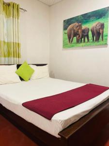 a bedroom with a bed with a painting of elephants at Lake Island Home Stay in Dambulla