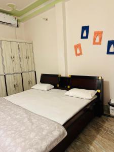 - une chambre dotée d'un lit avec des draps blancs et des photos bleues sur le mur dans l'établissement Paridhi, à Varanasi