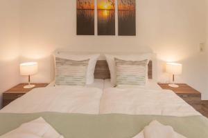 1 dormitorio con 1 cama con sábanas blancas y 2 lámparas en Villa Am alten Kreidebruch_ App_ S en Sassnitz
