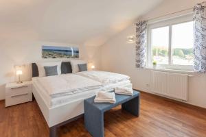 a white bedroom with a large bed and a window at Villa Am alten Kreidebruch_ Pentho in Sassnitz