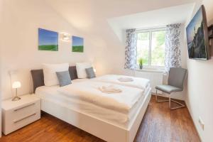 a bedroom with a large white bed and a chair at Villa Am alten Kreidebruch_ Pentho in Sassnitz