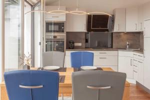 een keuken met een tafel en twee blauwe stoelen bij Villa Am alten Kreidebruch_ Pentho in Sassnitz