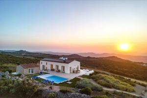 una imagen de una villa con una puesta de sol en el fondo en Sardegna è - Stazzu di l'Incantu con piscina, en Aglientu