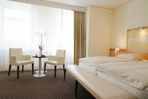 um quarto de hotel com uma cama, uma mesa e cadeiras em Park-Hotel am Rhein - Gesundheitshotel und Residenzen em Rheinfelden