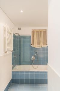 a blue tiled bathroom with a shower and a tub at Casa Penny - Menaggio by LoveComo in Menaggio