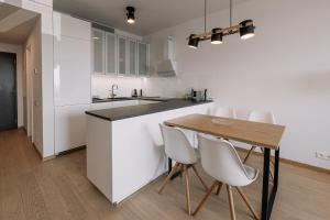 a kitchen with a wooden table and white cabinets at SKAU Blue Residence in Sky Park 21 floor 2 tower Panoramic View Free Parking in Bratislava