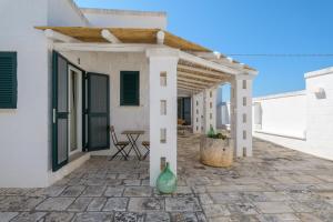 a white house with a pergola on a patio at Masseria Abadia Uno in Ostuni