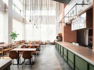 a restaurant with tables and chairs in a room with windows at REF Okinawa Arena by VESSEL HOTEL in Okinawa City