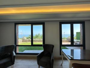 a dining room with three windows and a table and chairs at Sea View Villa in Trabzon