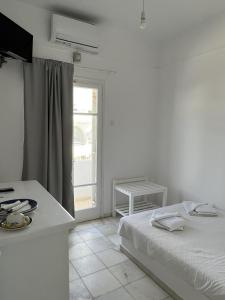 a white bedroom with a bed and a window at Hotel Anezina in Drios