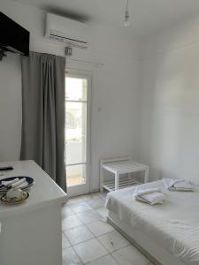 a white bedroom with a bed and a window at Hotel Anezina in Drios