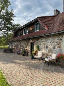 Casa de piedra con sillas y patio en Jeiskas dzirnavas en Launkalne