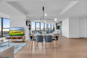 a dining room with a table and chairs and a tv at Luxe Panoramic 3 Bedroom Penthouse with onsite parking in Melbourne