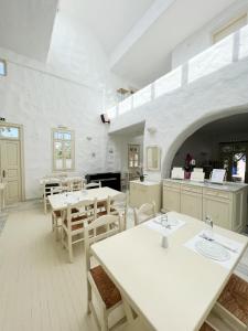 a white room with tables and chairs and a kitchen at Hotel Anezina in Drios