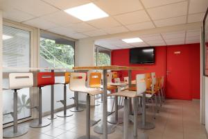 una sala de conferencias con paredes rojas, mesa y sillas en Premiere Classe La Ville Du Bois, en La Ville-du-Bois