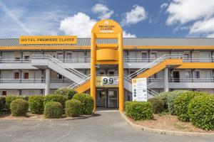 a hotel maintenance building with a large yellow building at Premiere Classe La Ville Du Bois in La Ville-du-Bois