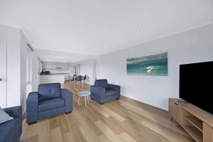 uma sala de estar com 2 cadeiras azuis e uma televisão de ecrã plano em Logans Beach Apartments - Greenviews em Warrnambool