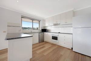 a kitchen with white cabinets and a large window at Logans Beach Apartments - Greenviews in Warrnambool
