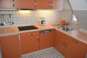 uma cozinha com armários laranja e um lavatório em Meene Menten Ferienwohnung Nr 04 em Süderhöft