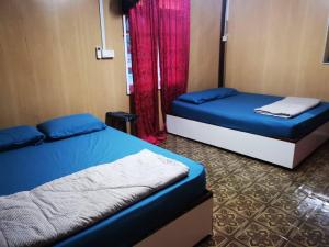 a bedroom with two beds and a red curtain at Homestay Pokdin in Kuantan