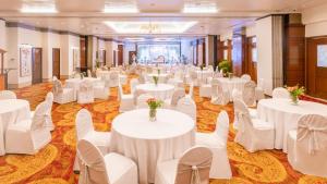 a banquet hall with white tables and white chairs at Hotel Kohinoor Continental,Airport in Mumbai