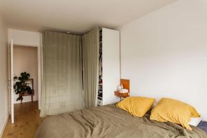 um quarto com uma cama grande e almofadas amarelas em Bright apartment with double terrace em Paris