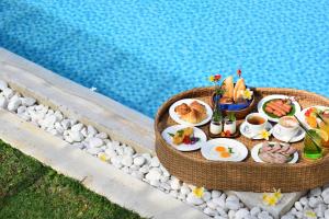 una bandeja de comida en una mesa junto a una piscina en Fleur de Lys Resort & Spa Long Hai, en Long Hai
