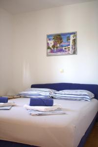 una cama con sábanas blancas y una pintura en la pared en Andrea Apartments, en Trogir
