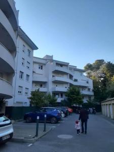a man and child walking down a street next to a building at T2 duplex + piscine avec parking in Montpellier