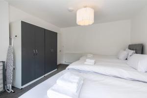 Un dormitorio con dos camas y un armario negro. en Gertrude House - Spacious 3BR Bungalow in Nottingham, en Nottingham