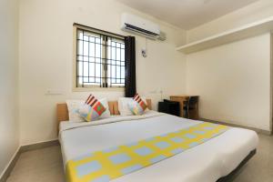 1 dormitorio con 1 cama blanca grande con almohadas coloridas en OYO Home Harma Residency Near Koyambedu Metro Station, en Chennai