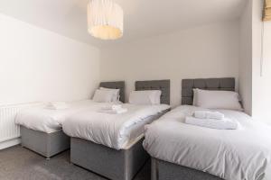 Habitación con 2 camas individuales y paredes blancas. en Gertrude House - Spacious 3BR Bungalow in Nottingham, en Nottingham