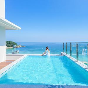 釜山的住宿－Paul Mare Pool Villa，坐在游泳池俯瞰大海的女人