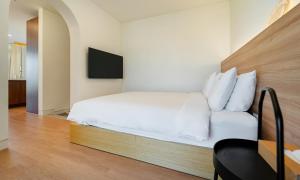 1 dormitorio con 1 cama blanca y TV en Paul Mare Pool Villa, en Busan
