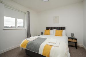 a bedroom with a large bed with yellow pillows and a window at A delightful flat in Manchester. in Manchester
